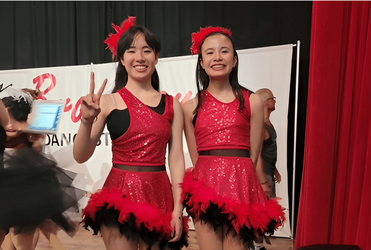 Two dancers in red sequin dresses smiling.