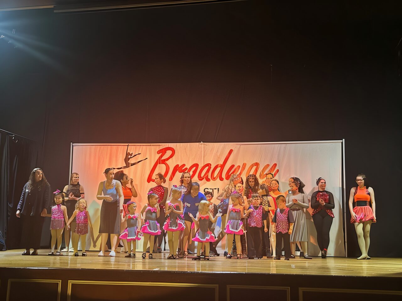 Dance group on stage with banner.