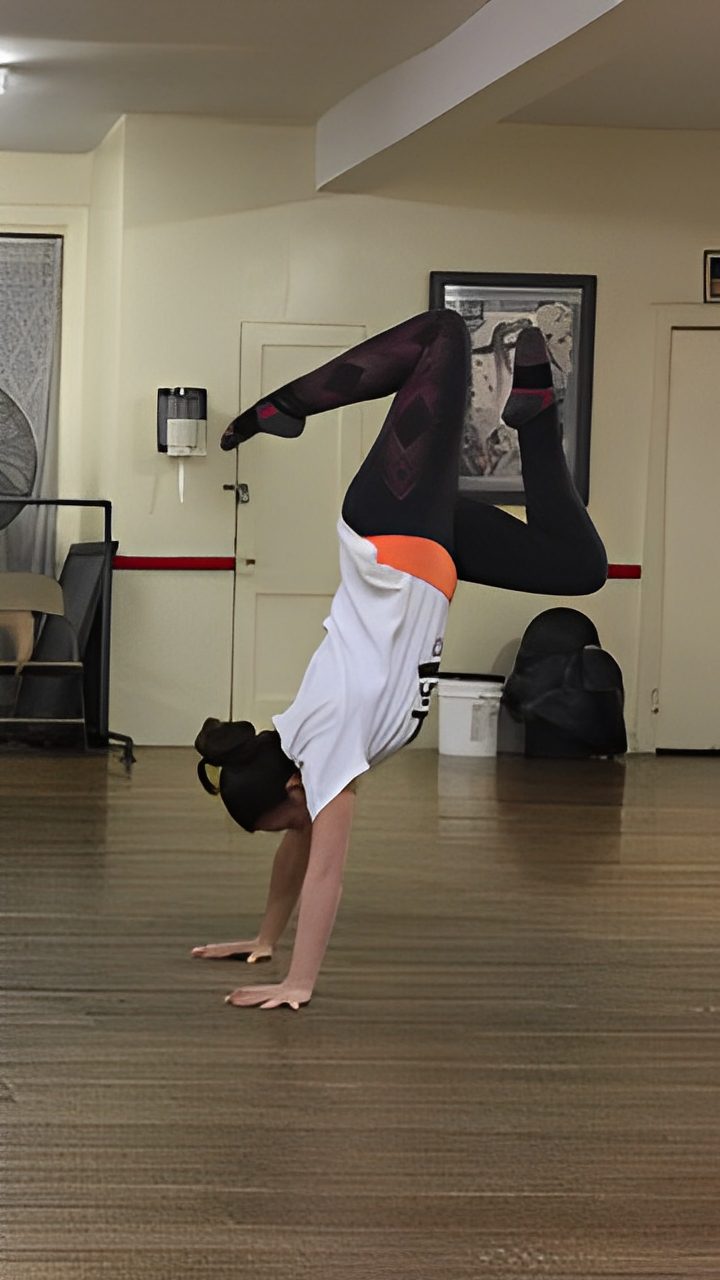 Person performing a handstand in a dance studio.