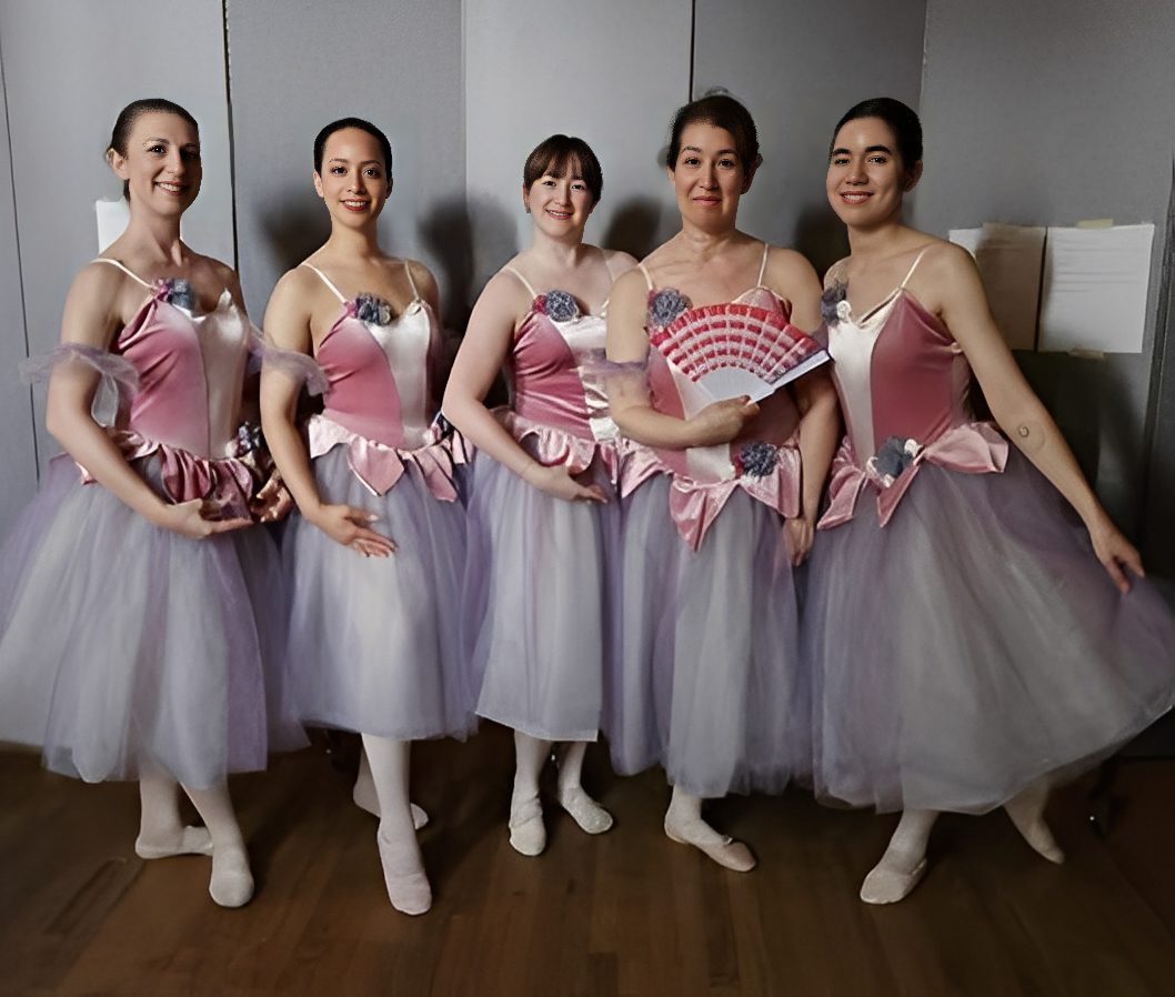 Five ballerinas posing in pink and white costumes with tulle skirts.