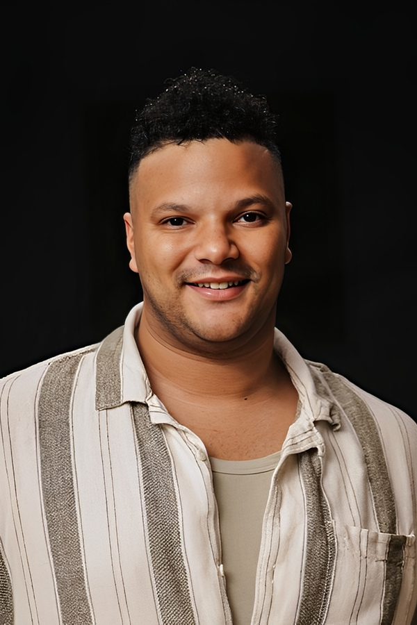 Smiling young man in a striped shirt against a black background.