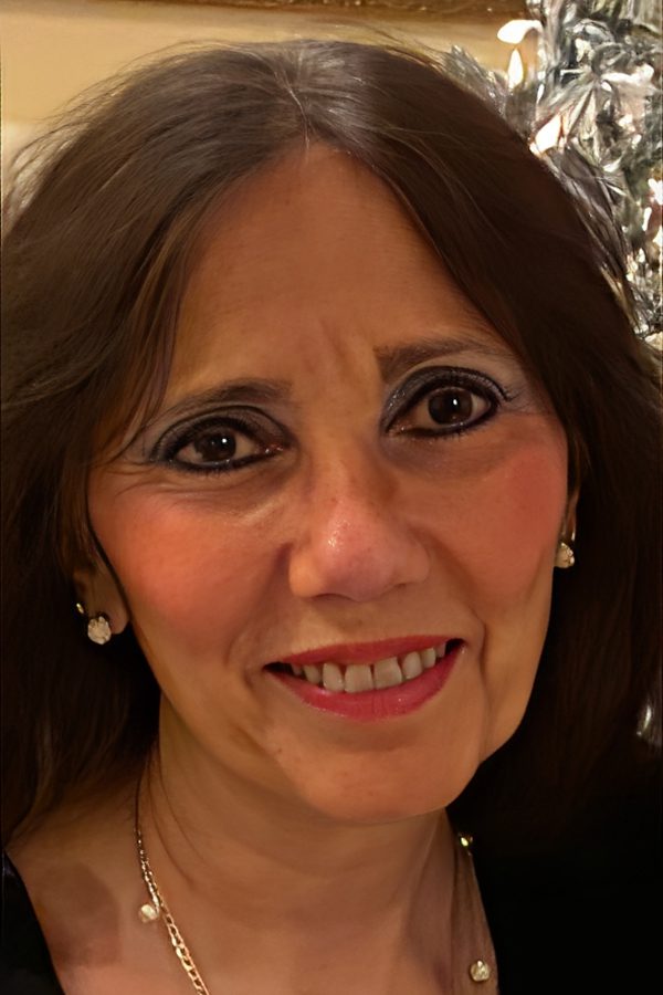 Close-up of a smiling woman with earrings and dark hair.