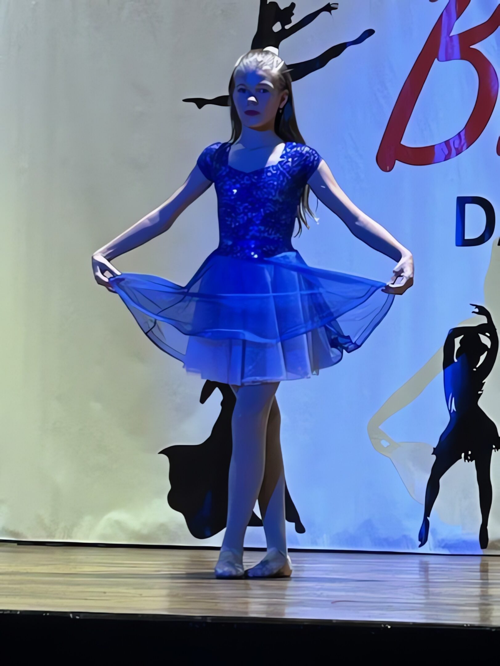 Young dancer in blue dress performing ballet.