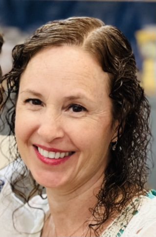 Smiling woman with curly hair and bright eyes.